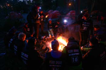 Campfire glowing under the night sky during an aurora-hunting evening